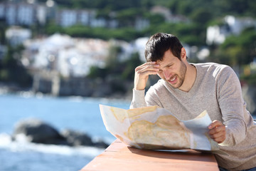 Worried tourist checking map in a coast town