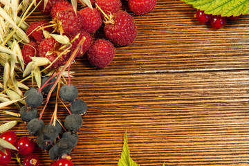 red currant, raspberry, leaves, cereals on a wooden background.room for text.