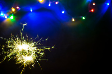 wunderkerze mit bunter lichterkette unscharf im hintergrund