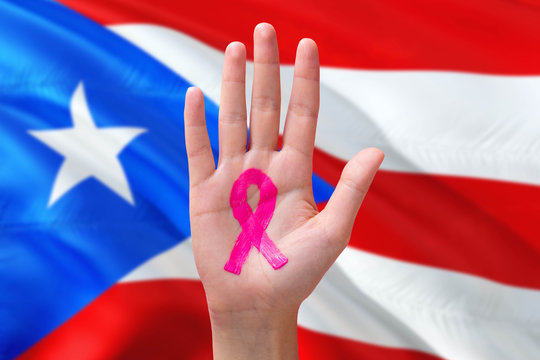 Puerto Rico awareness concept. Close-up awareness ribbon painted on palm on national flag background. October Pink day and world cancer day.