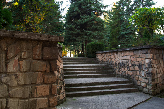 The stairs up. The stone steps. A wall along the steps. Park, city
