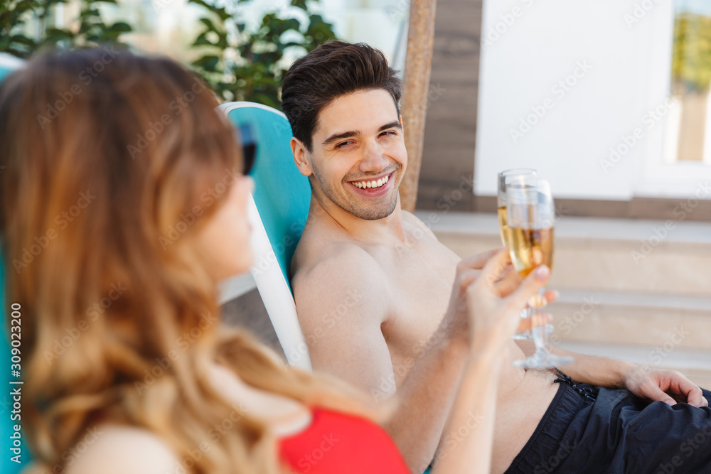 Sticker Loving couple near hotel outdoors lies on deck chairs