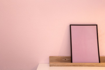 Pink blank mock up of photo frame on the light background. Home interior, wooden shelf near pink wall