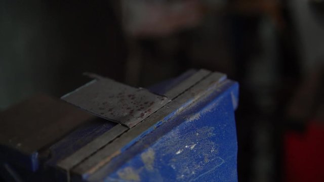 Bending metal in bench vice with hammer