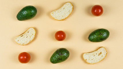 Flat lay of ripe avocado on yellow background, tomato and bread. Cooking and eating vegan sandwich.
