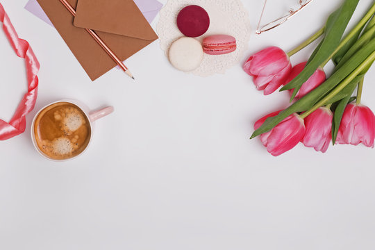 Beautiful pink tulips, cup of coffee and macarons on the white table