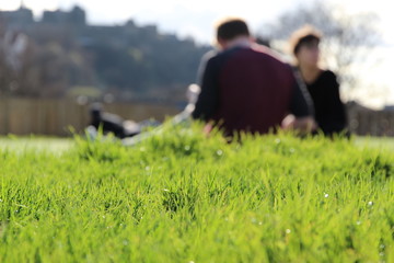 Naklejka na ściany i meble blurred man and woman sitting and talking in a park