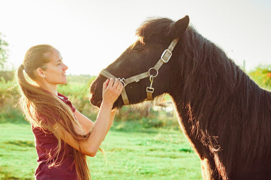 young beautiful girl strokes horse