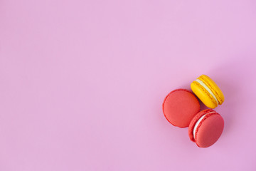 Three tasty french macarons on pink background. Pink and yellow macarons.