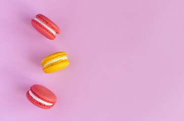 Three tasty french macarons on pink background. Pink and yellow macarons.
