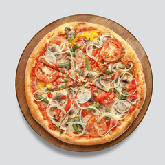 Appetizing pizza on a wooden board isolated on a gray background. Top view.