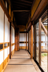 Traditional japanese ryokan house with shoji sliding paper doors tatami mat floor in corridor hallway leading to room by glass windows view of rock garden