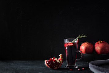 Pomegranate Christmas cocktail with rosemary, champagne, club soda on black table. Xmas drink.