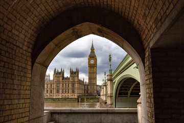 Big Ben (officially known as the Great Bell in the Elizabeth Tower), viewed across the River Thames and framed by a bricked arch.