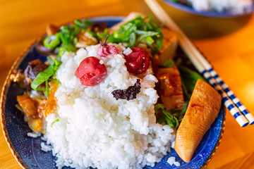 Traditional japanese plate on wooden table and vegetable dish with white rice shiso, umeboshi, chopsticks and bamboo shoots with green onions