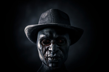 Scary figure with creepy bloody mask and hat in the dark