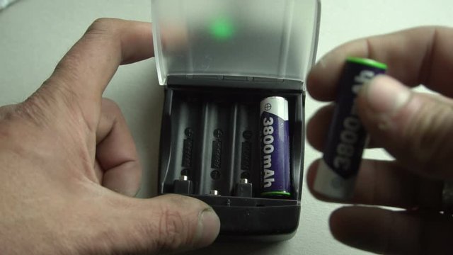 a person is charging AA batteries in the device