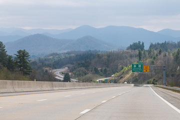 Smoky Mountains in North Carolina near Tennessee border with cloudy sky and forest trees on i26 highway road with exit sign