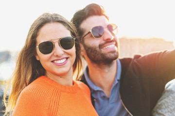 Beautiful couple of young people wearing sunglasses enjoying life in the summer. She's looking at...
