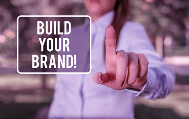 Handwriting text writing Build Your Brand. Conceptual photo creates or improves customers knowledge and opinions of product Woman in a blue business shirts pointing with her finger into empty space