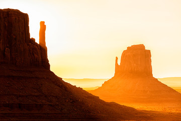 View closeup of famous mesa butte formations with red orange rock color on horizon in Monument Valley canyons during sunrise in Arizona - obrazy, fototapety, plakaty