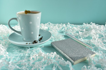 Caramel tree. Silver notebook with a white pen on a blue background with white paper and a cup of green tea. Colorful concept. Christmas background. Christmas. Card.