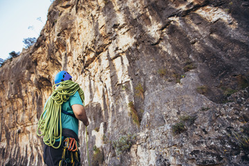 Man with a rope engaged in the sports of rock climbing on the rock.
