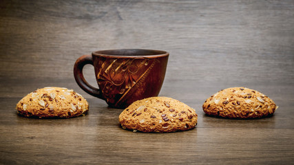 Mug of tea and oatmeal diet cookies on a wooden table in warm colors_