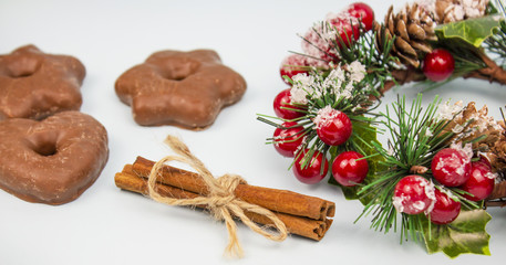 Obraz na płótnie Canvas Christmas composition with chocolate gingerbread cookies and cinnamon, Christmas wreath and chopsticks on a light background. Cinnamon. banner. place for text