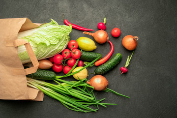 on a black background a paper bag from a supermarket with vegetables