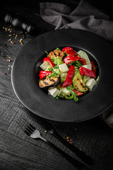 Grilled vegetable salad: zucchini, eggplant, bell peppers, herbs and feta cheese. Nutritious, dietary, fitness food. Black boards background