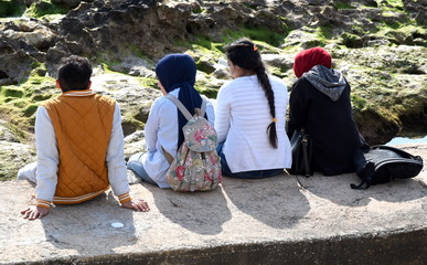 Naklejka premium Junge Leute auf einer Mauer am Strand sitzend