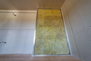 Wall of a room under renovation with mineral rock wool insulation and metal frame prepared for drywall plates.