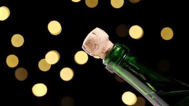 Champagne explosion. Champagne popping, opening champagne bottle closeup. Sparkling Wine over Holiday Bokeh Blinking dark Background. Party, Success, holiday celebrating. Slow motion 
