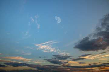 Blue sunset sky covered with white puffy clouds.