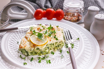 Vegetarian lasagna with spinach and microgreens on a white plate. Tasty and healthy food.