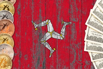 Isle Of Man savings concept. Bitcoins and dollar banknotes on the side of national flag with wooden...