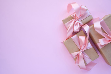 Beautiful present on pink background. Gift kraft package with ribbon and pink bow. Surprise for Christmas, Valentines Day or Mothers Day. Happy holiday mockup. Celebration event. Gift box close-up