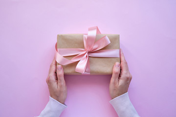 Beautiful present on pink background. Gift kraft package with ribbon and pink bow. Surprise for Christmas, Valentines Day or Mothers Day. Happy holiday mockup. Celebration event. Gift box close-up