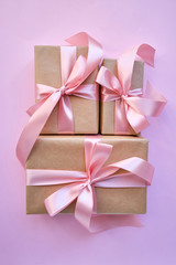 Beautiful present on pink background. Gift kraft package with ribbon and pink bow. Surprise for Christmas, Valentines Day or Mothers Day. Happy holiday mockup. Celebration event. Gift box close-up