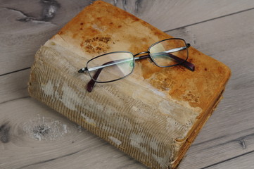 Optical glasses and old book on grey woodboard