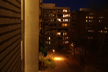 dark night courtyard with luminous windows of an apartment building with a lantern, urban concept