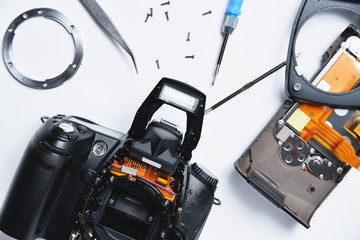 Parts of electronics in a service center. A disassembled camera on a table with tools and components.