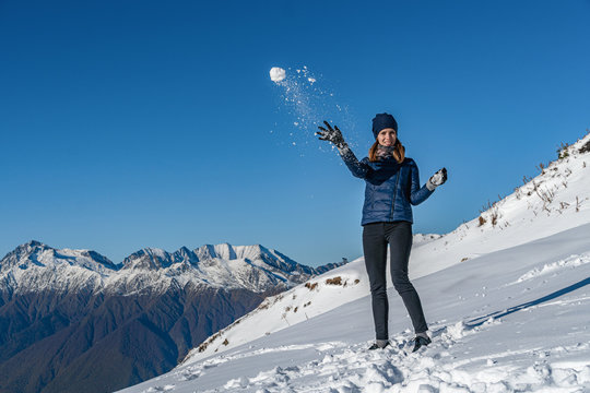 Happy young woman playing snowball fight on the snow day. winter and people concept