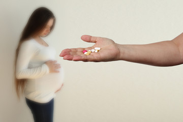 female hand holds out, offering, a handful of colored pills and capsules, close-up, blurred image...