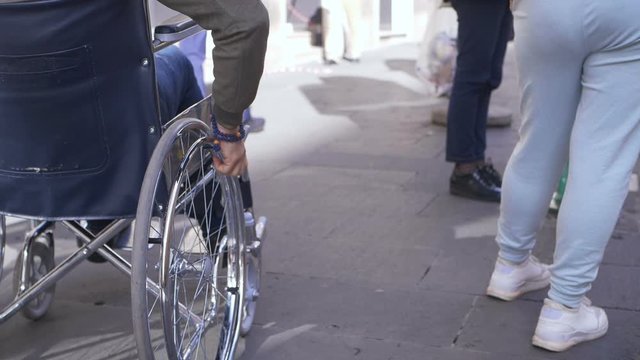 disabled man pushing  wheelchair on crowded sidewalk.handicaps,autonomy
