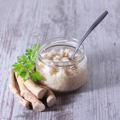 Spicy horseradish sauce in glass jar isolated on white