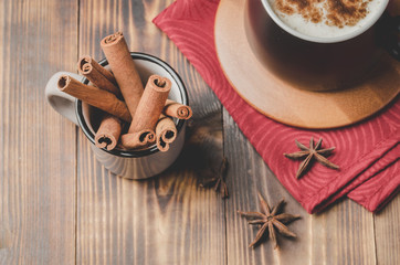 Eggnog. Traditional christmas cocktail in a black mug on a red napkin with cinnamon sticks and anise on wooden table. Top view.
