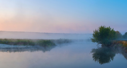 Morning dawn over a river covered in fog.
