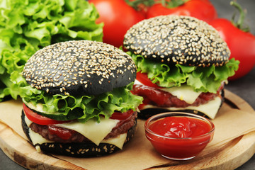Two black burgers with vegetables and beef meat	